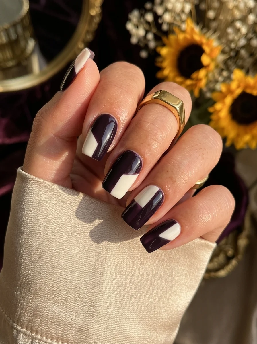 Square nails with bold diagonal color blocking in dark plum purple and cream white.