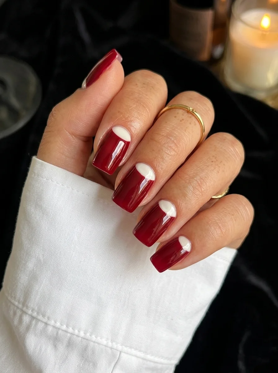 Coffin nails with deep dark red base featuring white half-moon shapes at the cuticle area creating a reverse French effect.