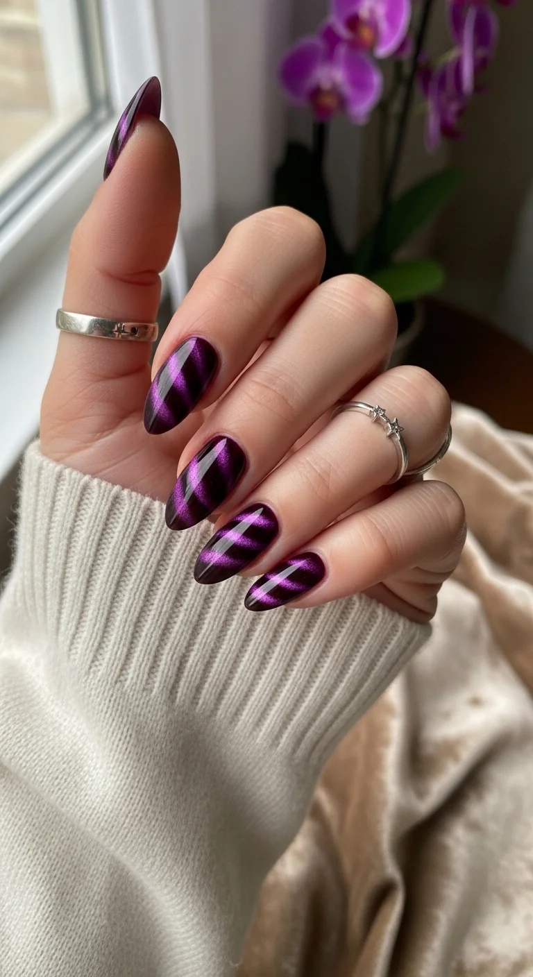 Almond nails with purple magnetic cat-eye effect in diagonal stripes.