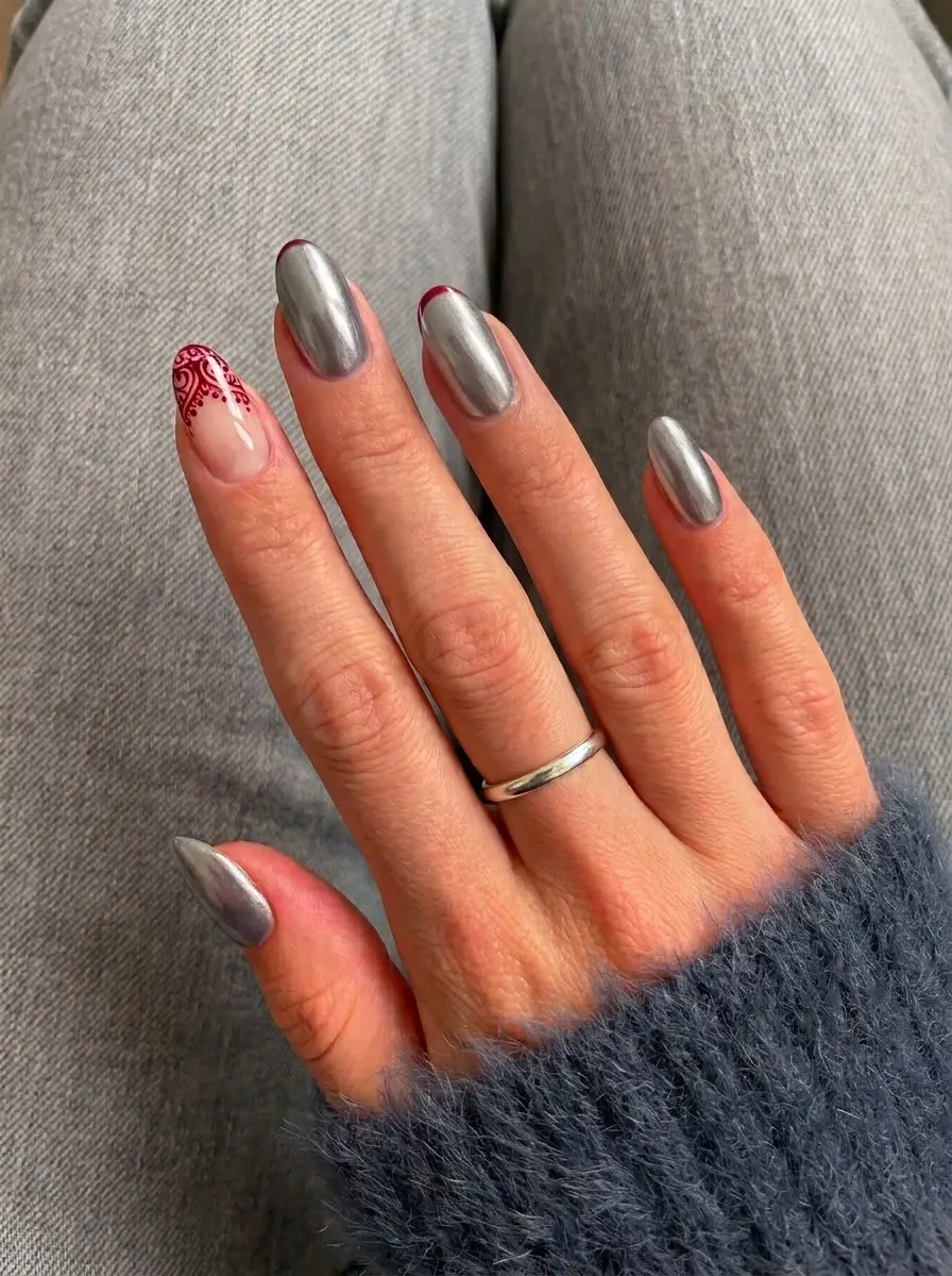 Silver Chrome Christmas Nails With Red Detailing - Mirror-like silver chrome short rounded nails with burgundy edging and red ornamental swirls