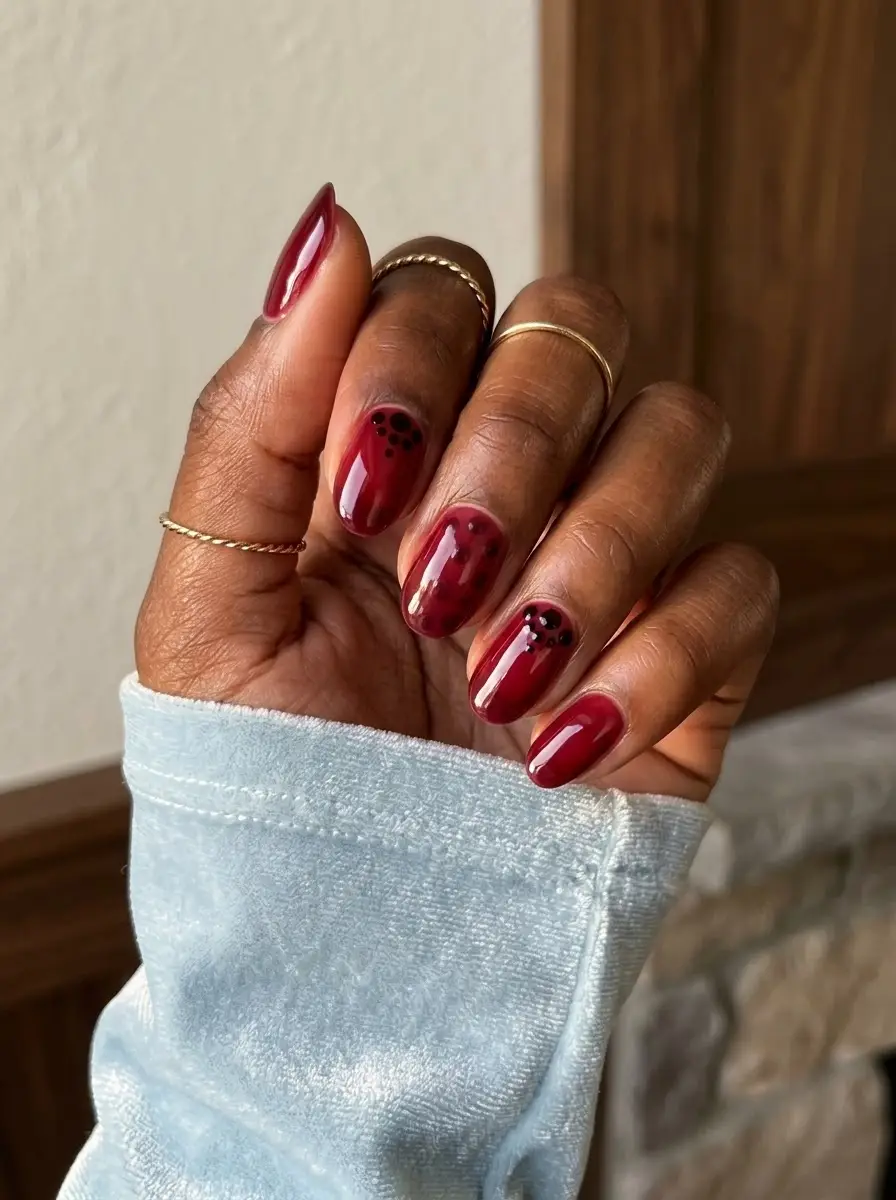 Cranberry Jelly Nails with Black Dot Clusters - Glossy translucent cranberry-red jelly nails styled with tiny black dot clusters near the cuticle