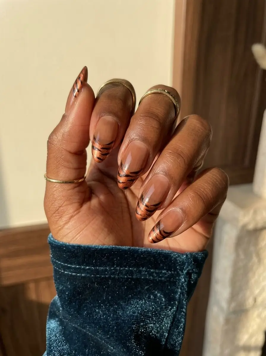 Copper Tiger-Stripe French Tips - Sheer almond nails finished with metallic copper French tips and thin curved black tiger stripes