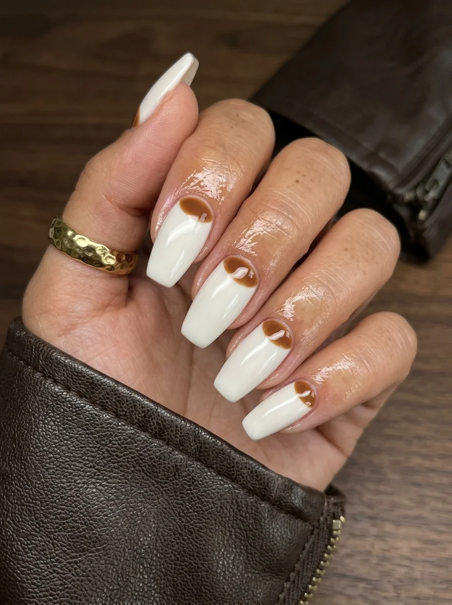 Long coffin nails with a white base and brown coffee-colored swirl patterns concentrated at the cuticle area.