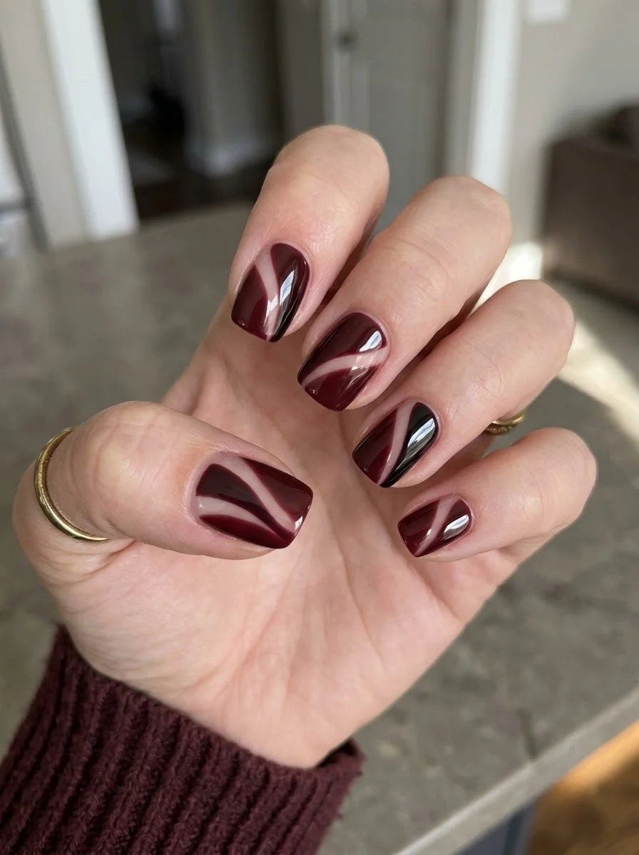 Dark burgundy nails with white swirl design
