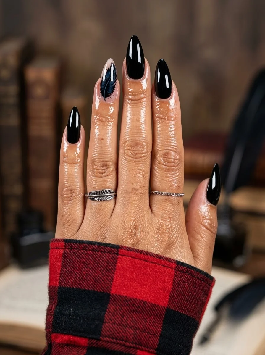 Glossy black almond nails with a sheer accent nail featuring a black feather design.