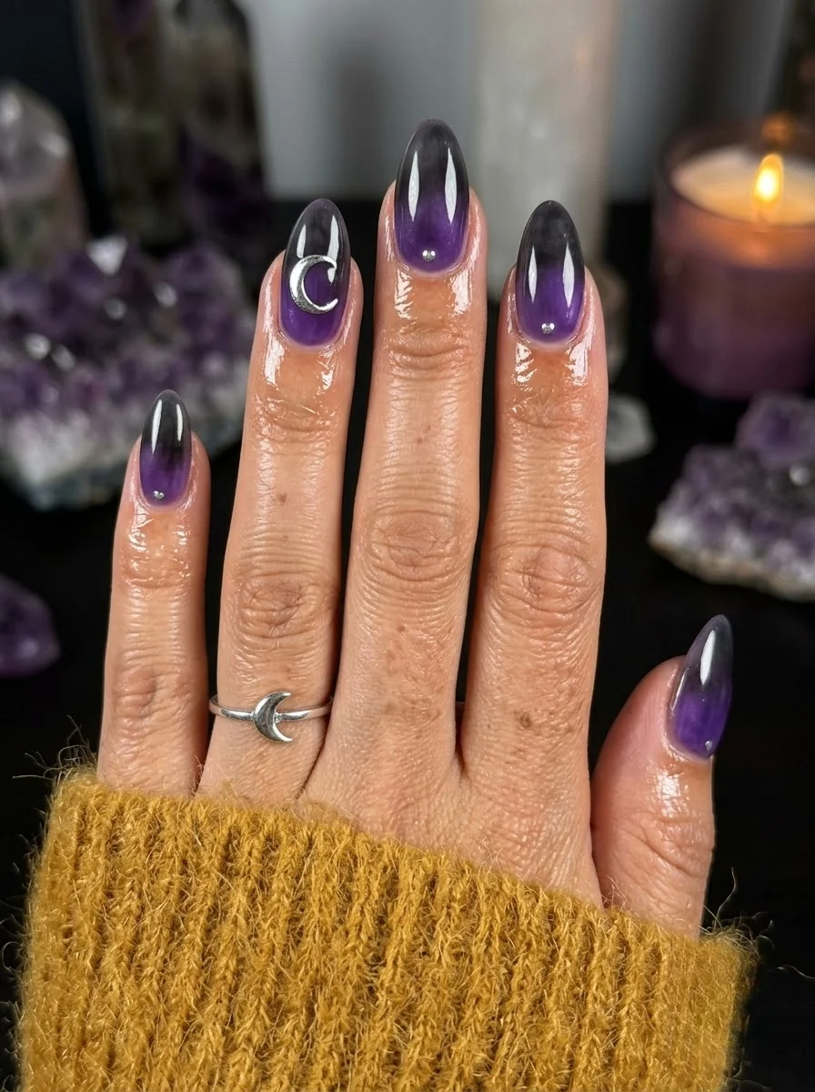 Almond nails with a purple to black gradient and a silver crescent moon accent on one nail.