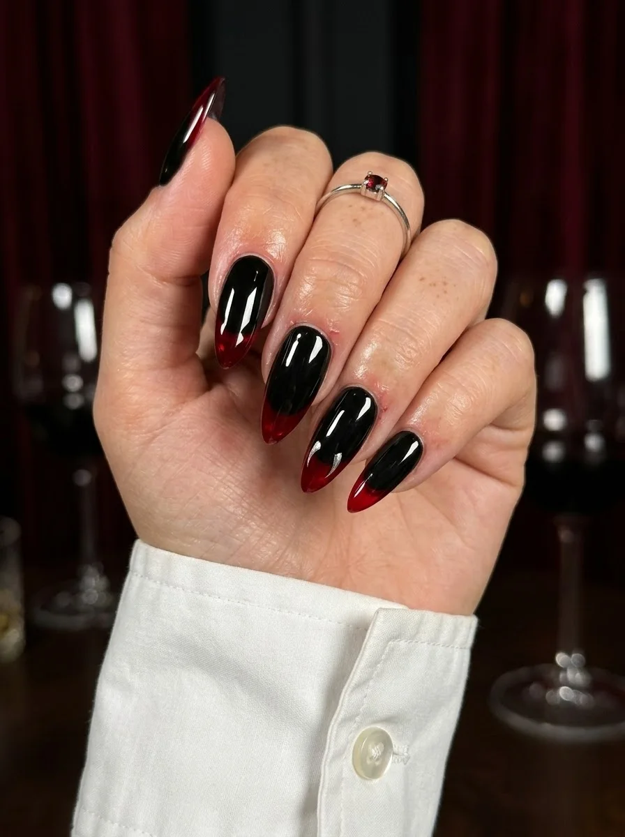 Stiletto nails with a black to deep red gradient, black at the cuticle fading to blood red at the tips.