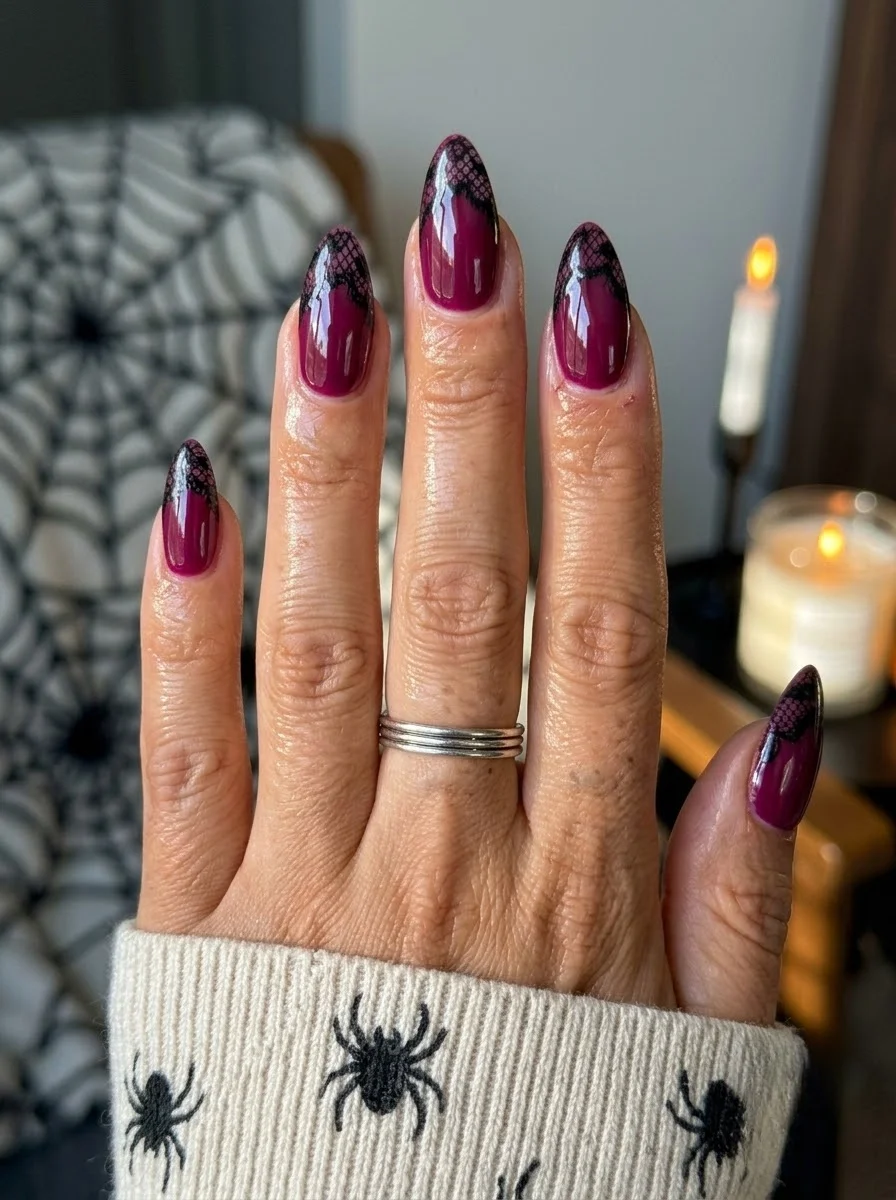 Deep magenta berry almond nails with black lace patterns at the tips.