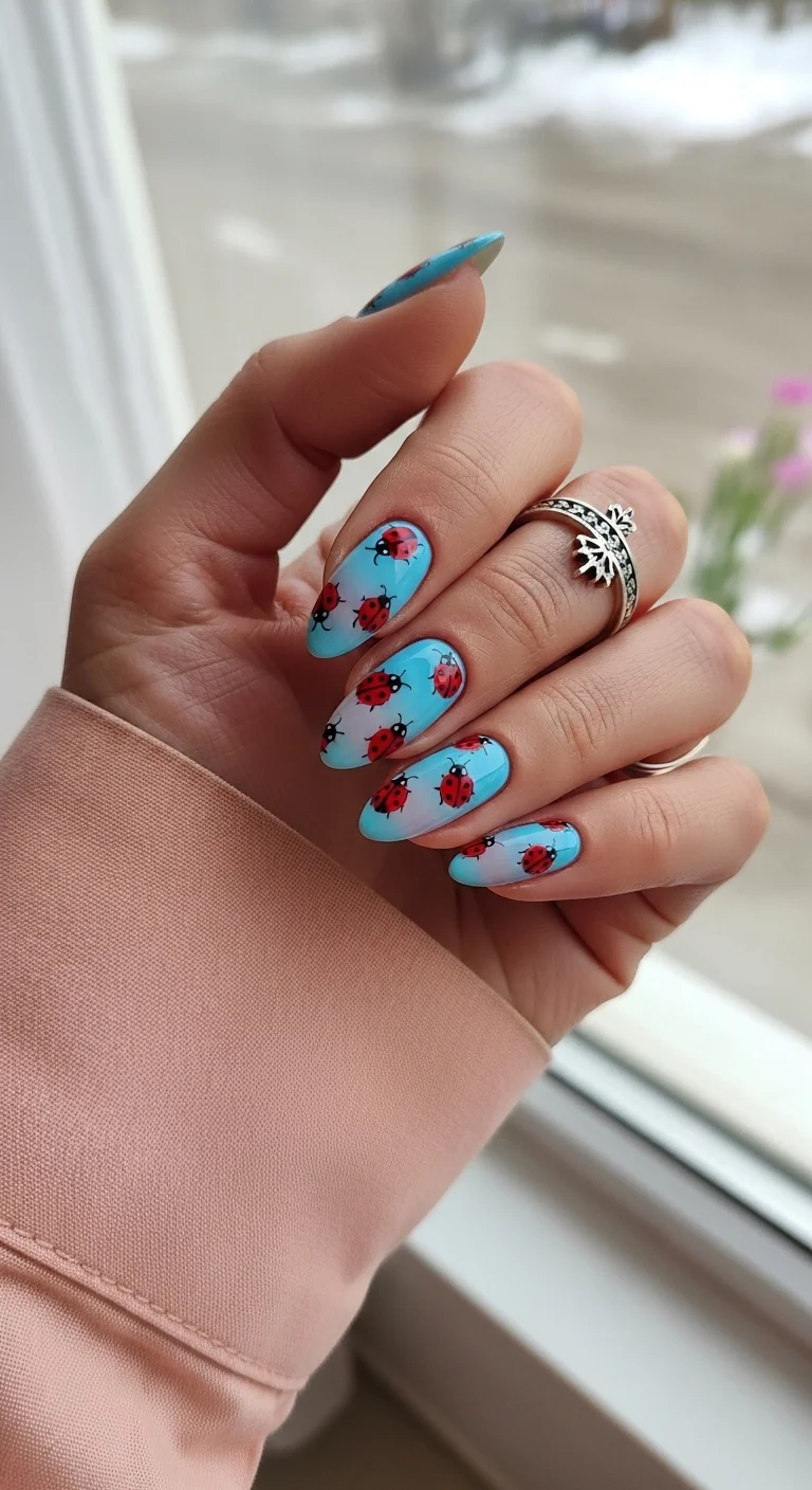 Oval nails with a blue and white sky ombre and ladybugs.