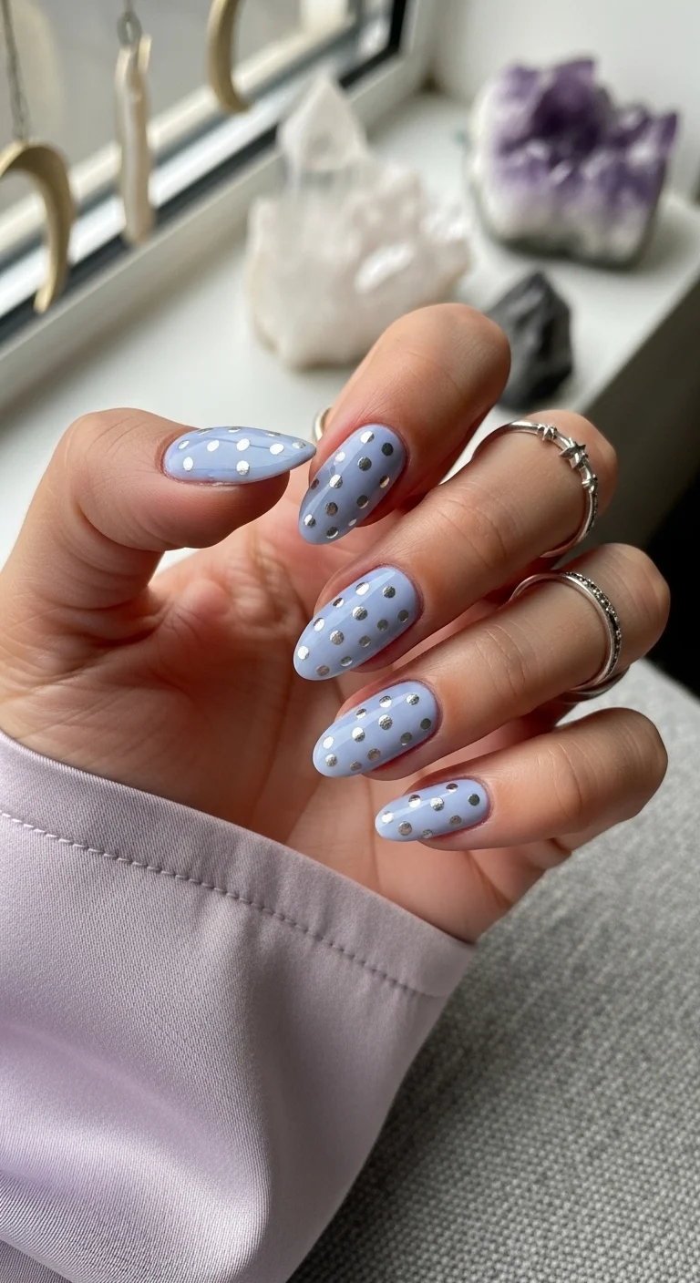 Oval nails in periwinkle blue with silver metallic dots.