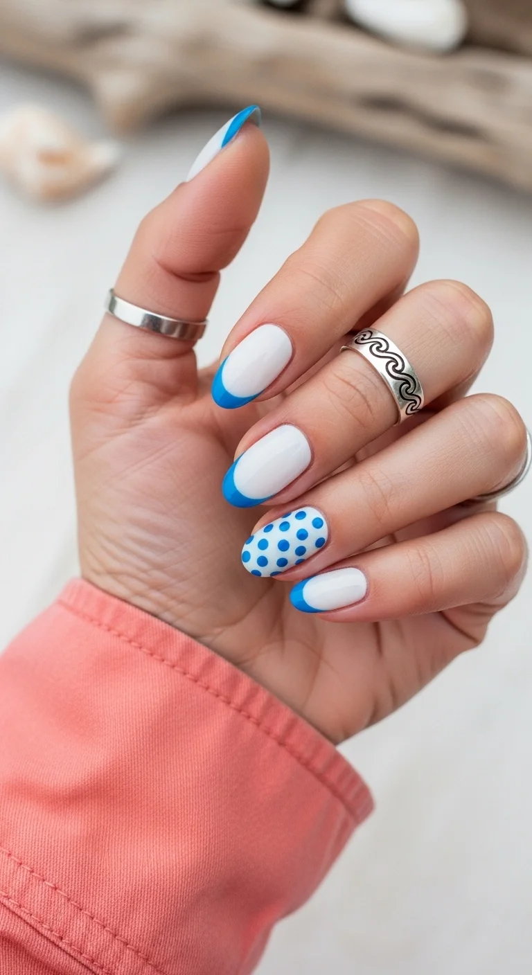 Oval nails with white base, blue French tips, and a blue polka dot accent nail.