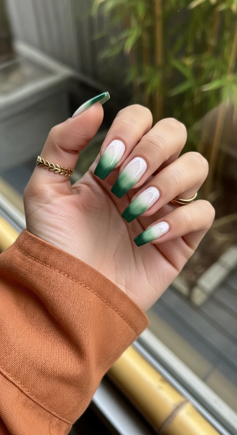 Long coffin nails with a milky base and a deep forest green ombre tip.