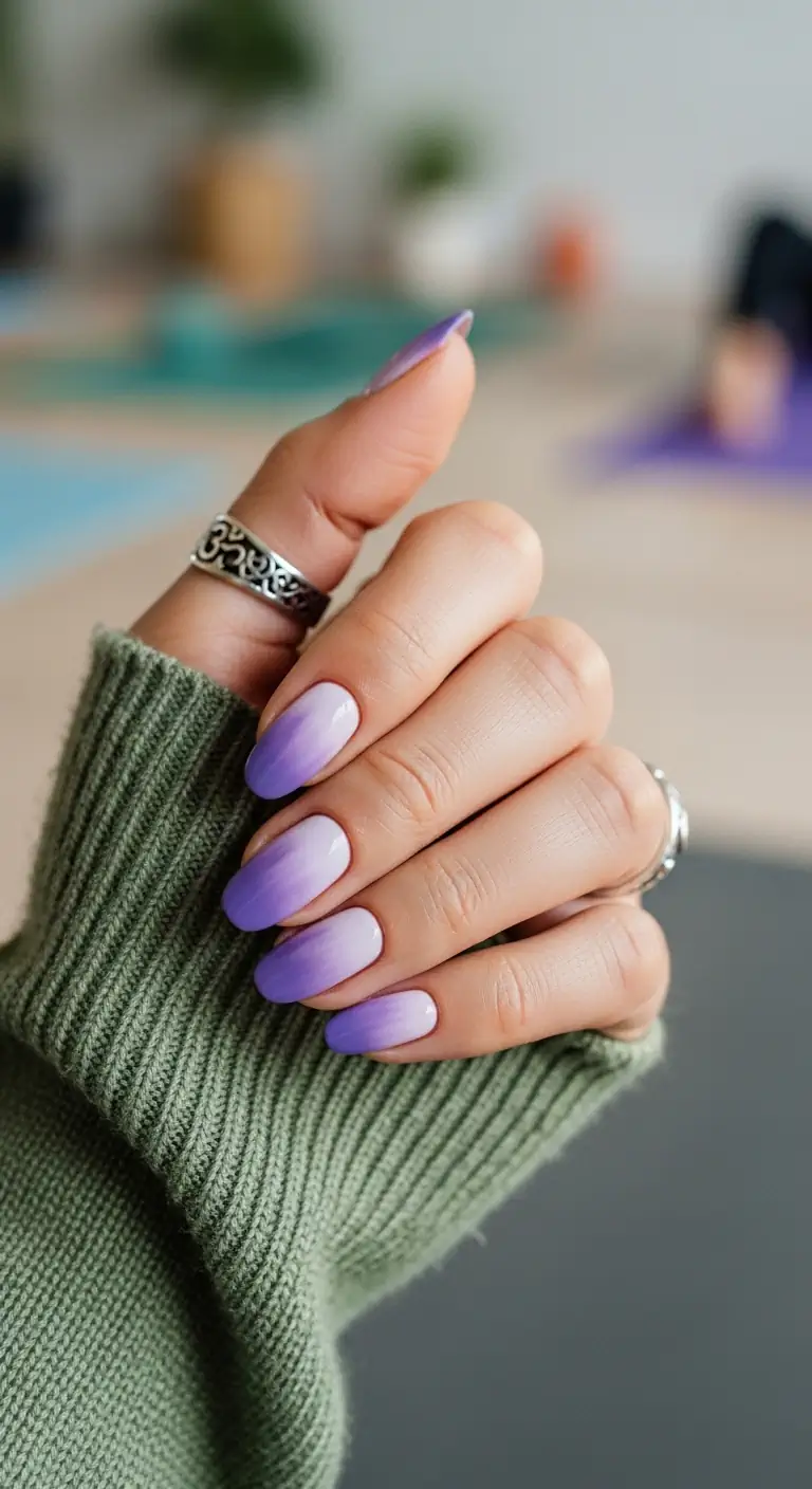 Medium oval nails with a seamless gradient fading from soft lilac at the tip to pale pink at the cuticle, in a yoga studio setting